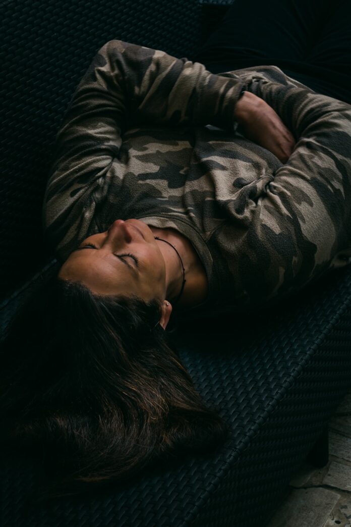 Photo by Gabriella Clare Marino woman in gray and black camouflage jacket lying on black couch