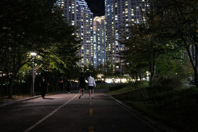 People jogging on a path at night near apartments.