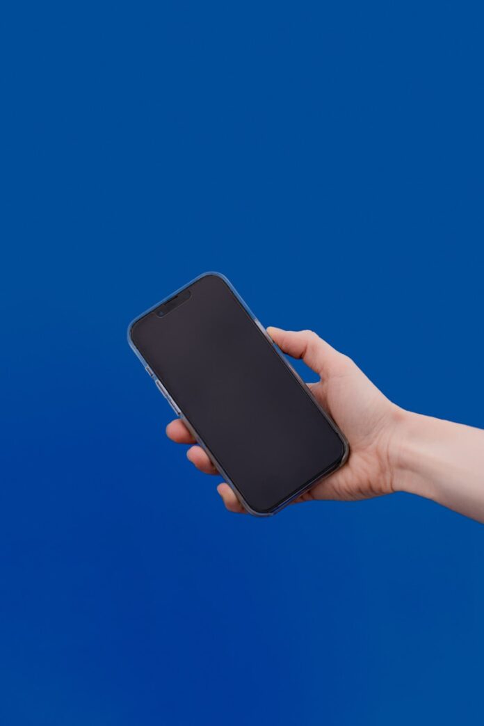 Photo by Anastasiya Badun a hand holding a cell phone against a blue background