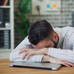 만성피로, 일상 속 작은 변화로 극복한다 a man sitting at a desk with his head in his hands